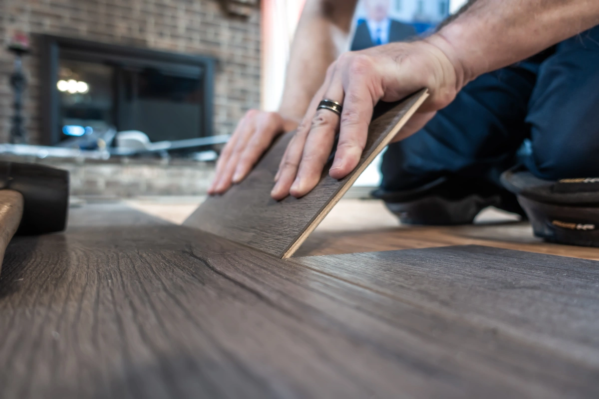 worker installing laminate flooring in room